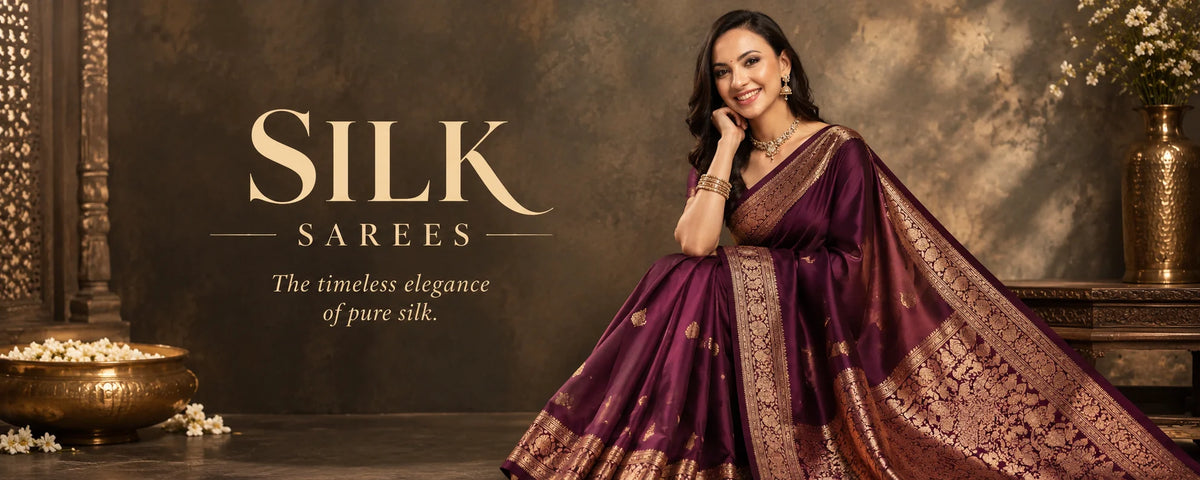 A woman wearing a rich purple silk saree with gold zari embroidery.